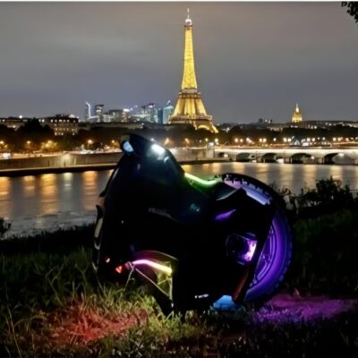 Gyroroue Nosfet Aero équipée de LED multicolores, photographiée de nuit à Paris avec la tour Eiffel illuminée en arrière-plan.