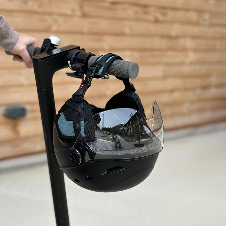 CASQUE URBAN MOOV VISOR 9 Casque Urban Moov Visor noir accroché au guidon d'une trottinette électrique